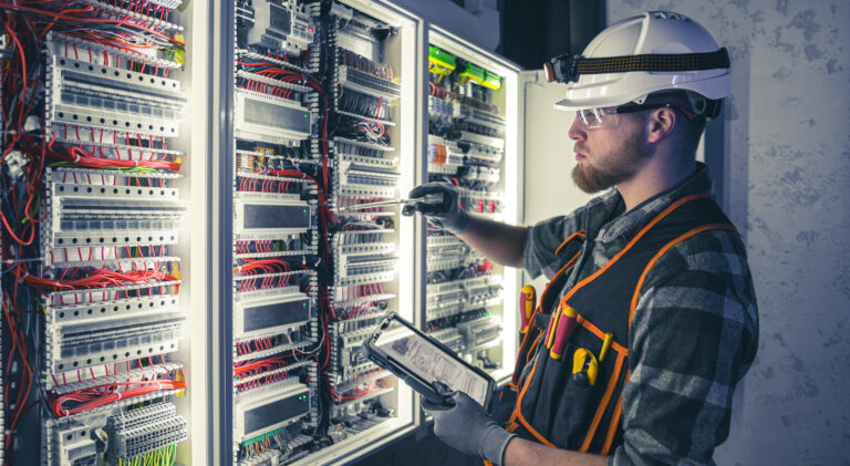 Electrician focused on work in switchboard with fuses, using tablet. Young adult electrical engineer in special clothes with flashlight on helmet in dark room with emergency lights in background. SSUCv3H4sIAAAAAAAAA41Py46DMAz8F5+DxKtd4FeqPYTEhaiBVImzVYXy7+sA1V43J3vGmccGRsMAWl51W+uyUNi3RVXhvRj7Uhbqq22xazp1VRoEnxHCUDVNV9VNXV7qS1+V/ASMMhgFwwbG2hjISzJuhYEZj6tGv4+oDTlvpOUtCQgkKQYM/I03xdoTs/v+0bttGeeAbB7imIck/ol9C5ATruqd9VMOYlHudjemHi9Cv5zejuYckUVcXMm/DyHr3FOOlhvfpQ0oYJYh8IE+Af749EaZdTobcHG3HPPqKDvteciph9Gn1VF6Noxmnw3i0zqpUZ90HBdD9Fk9/hh8/V2nlH4Bu48wSbIBAAA=